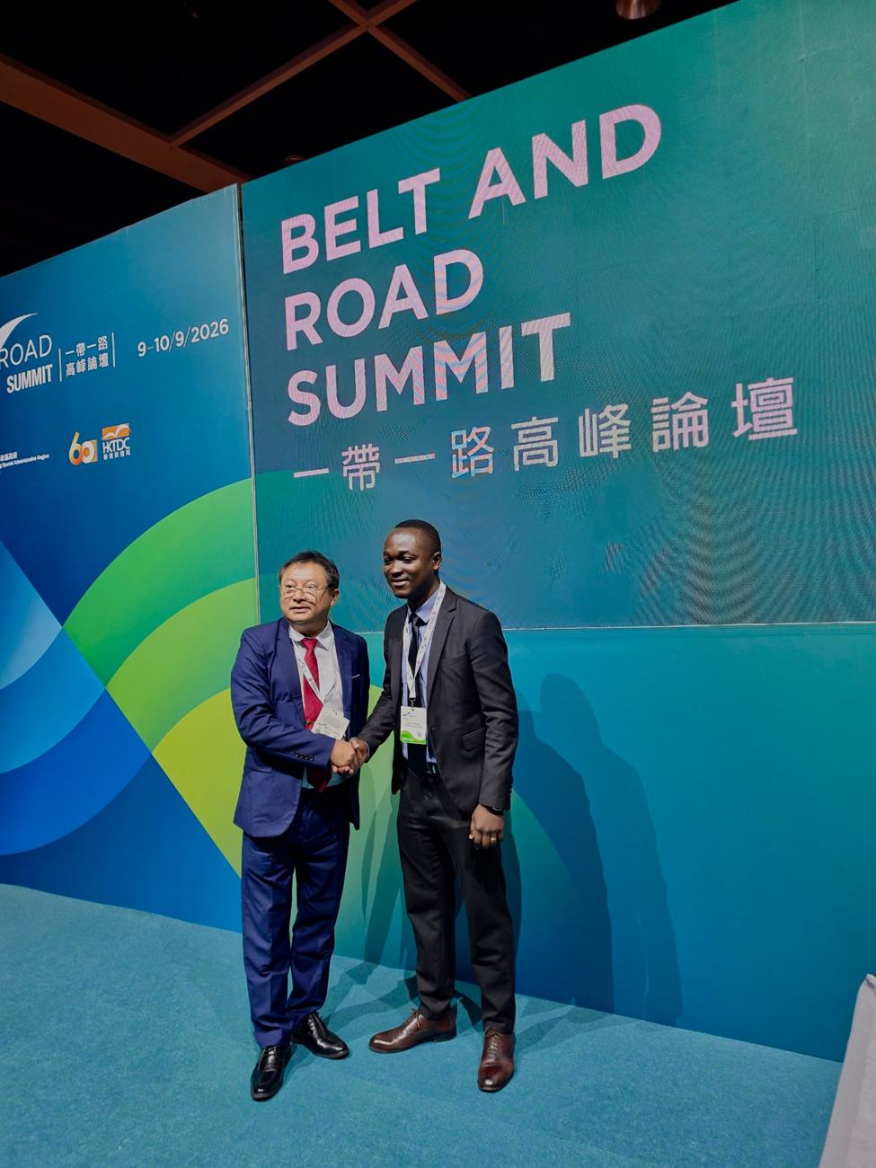 A Tanzanian delegate greets a counterpart in front of the Belt and Road Summit backdrop